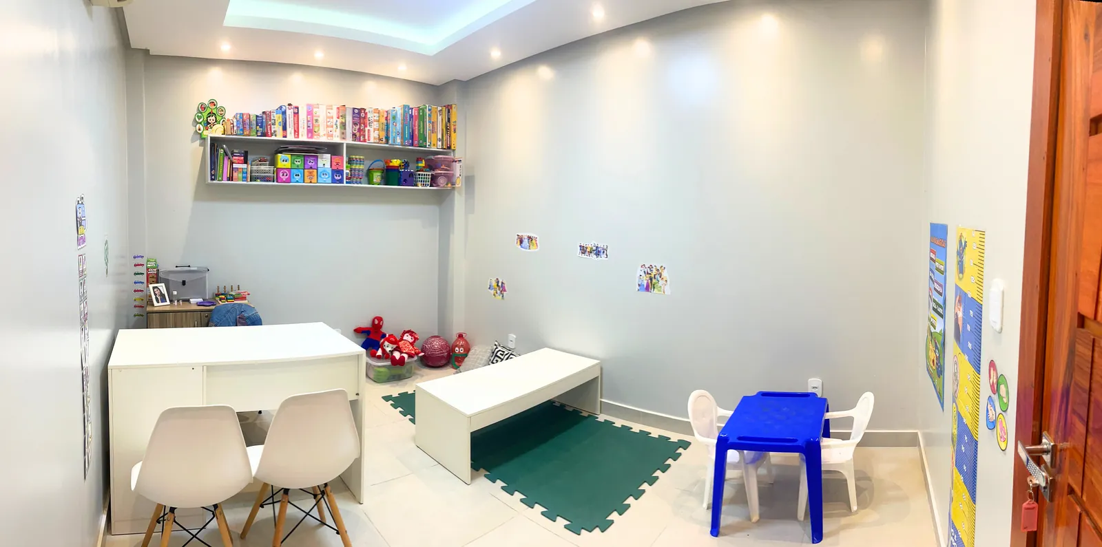 Sala de psicologia, com prateleira de jogos, mesinha infantil e tatame de EVA.