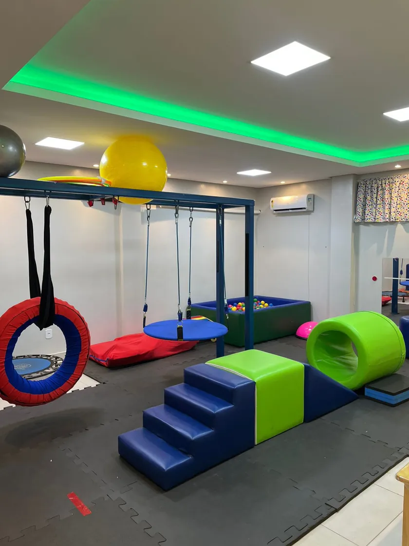 Sala de psicomotricidade, com balanço de pneu, túnel e escada de espuma e bolas suíças.